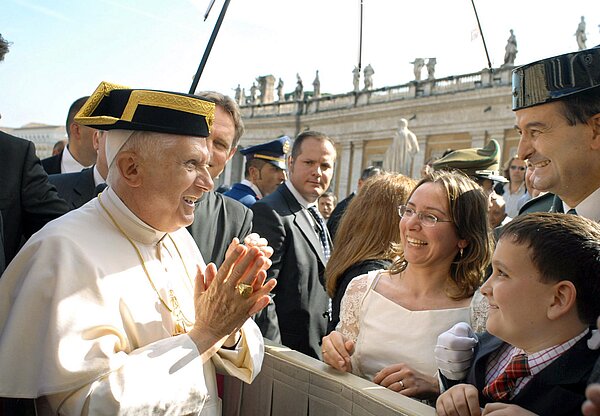 Papst Benedikt XVI. trägt eine spanische Kopfbedeckung und spricht heiter mit Pilgern